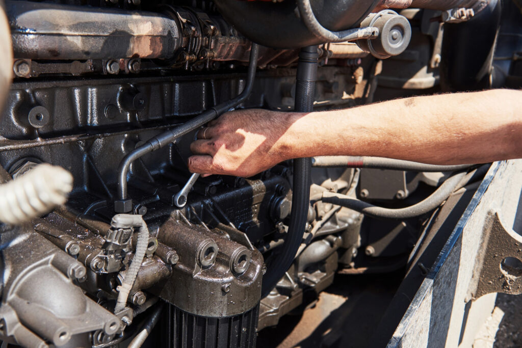 man reaching into an rv engine with a wrench in order to repair it